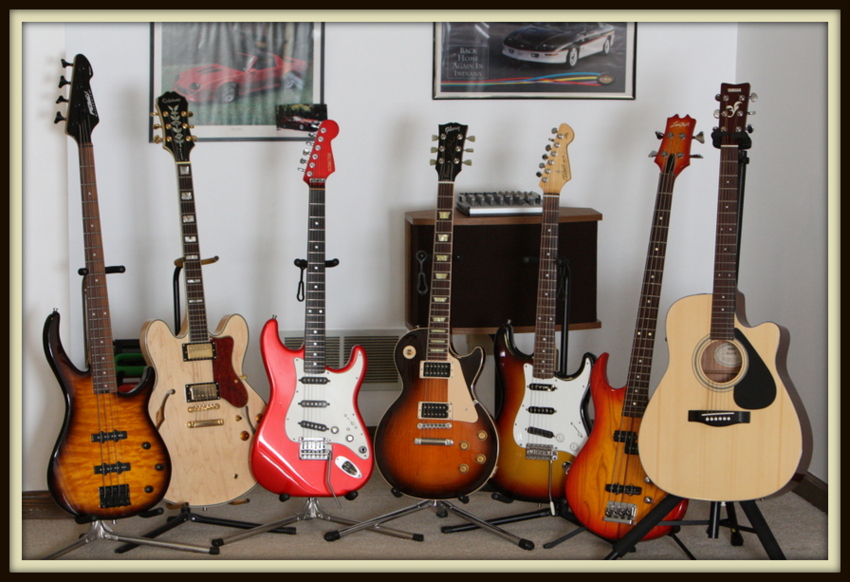 Left to right: Peavey Millennium BXP Bass, Epiphone Sheraton II, Schecter Strat, Custom Gibson Les Paul, Custom Tokai Strat AST-62, Custom Sigma Bass, Yamaha FG-411 CE Acoustic